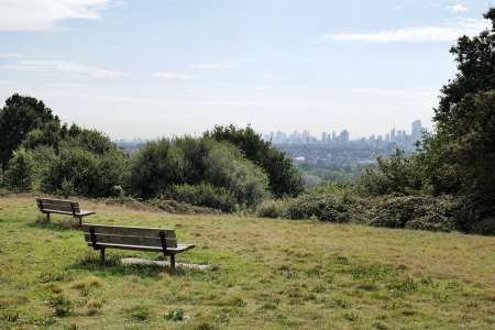 Skyline of London as seen from the benches on top of Parliament Hill in Hampstead Heath public park.