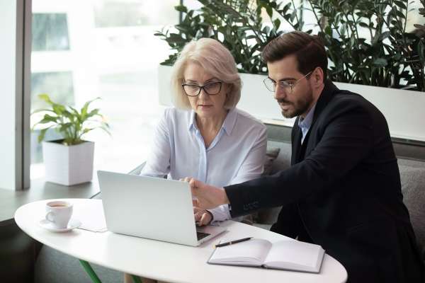 man and woman sat at laptop on white desk